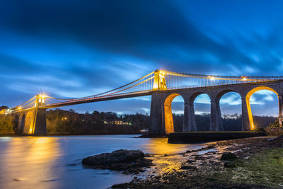 View of bridge over river at night