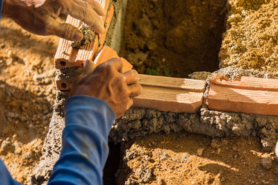 Cropped hand placing bricks in cement