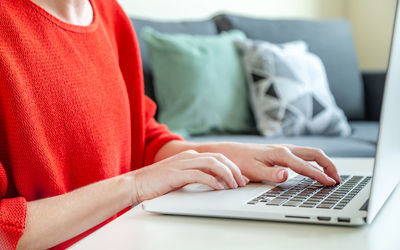 Freelancer working on laptop from home, hands in frame