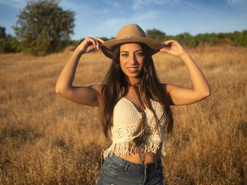 Young woman wearing hat standing on field