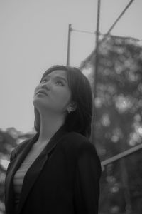 Portrait of young woman looking away against sky