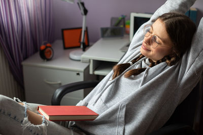 A teenage girl drags herself along while reading her school reading.