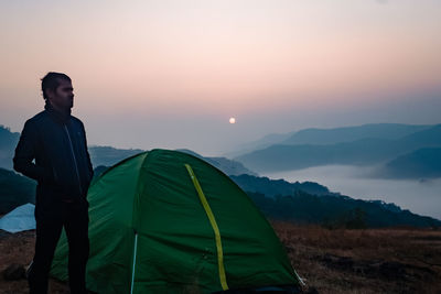 Man standing on mountain against sky during sunset