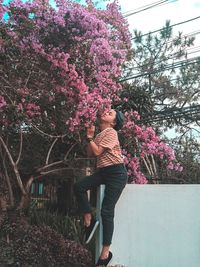 Woman standing by pink flowering tree