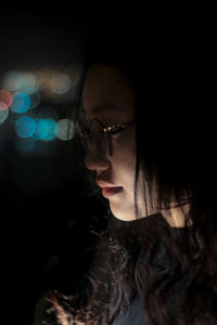 Close-up of young woman against black background