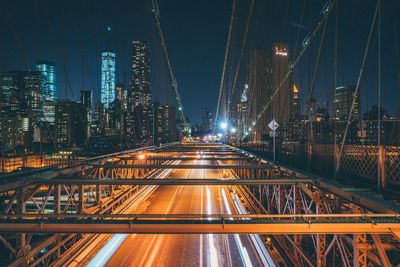 Illuminated bridge and buildings against sky at night