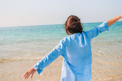 Rear view of man standing at beach against sky