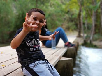 Portrait of smiling boy sitting with mother on pier