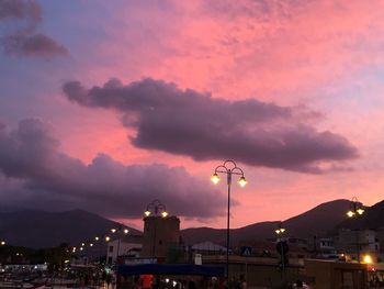 Illuminated city against sky at sunset