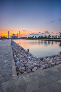 Scenic view of lake against sky during sunset in city