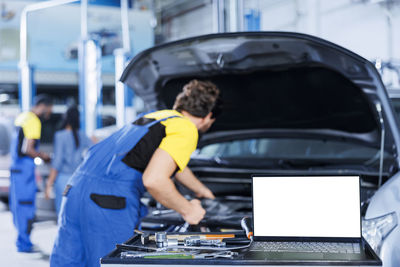 Rear view of man working in car