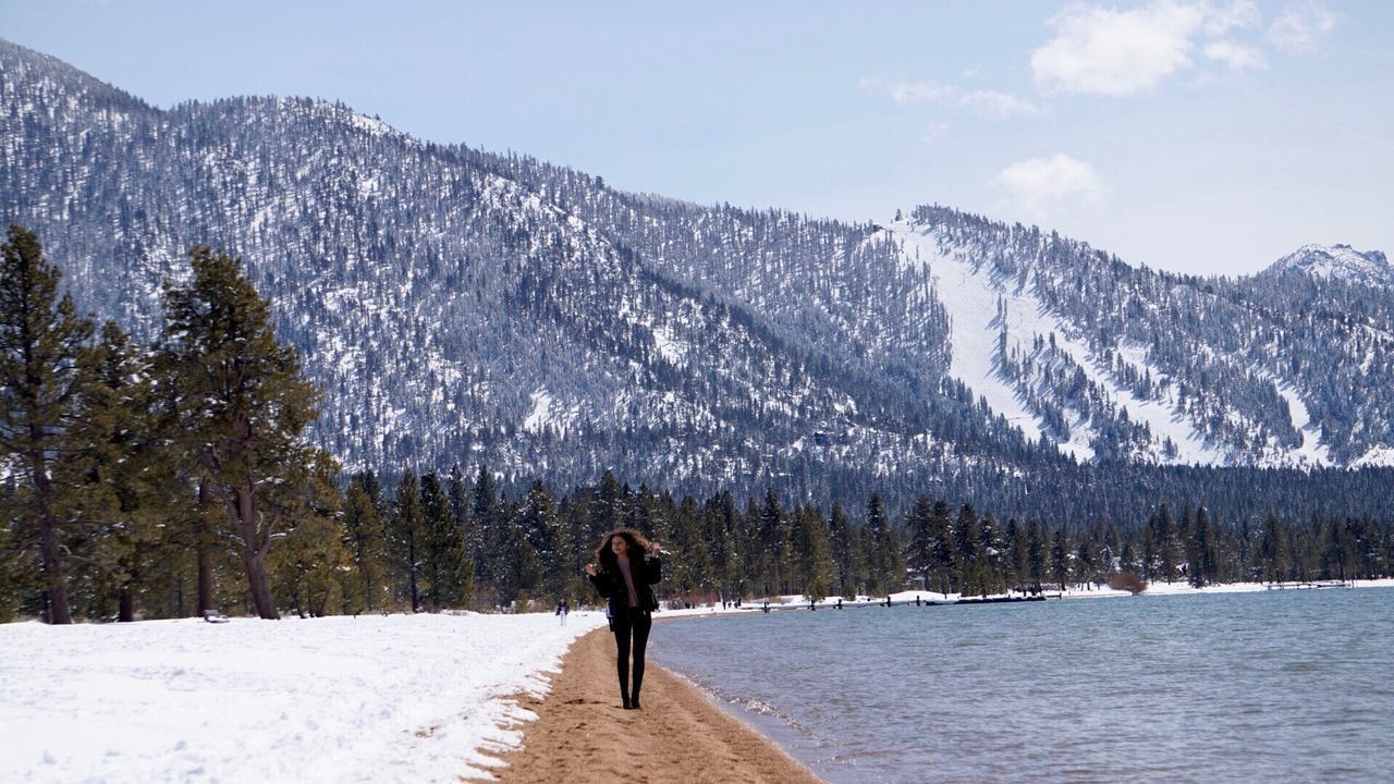 REAR VIEW OF PERSON WALKING ON SNOW COVERED MOUNTAIN