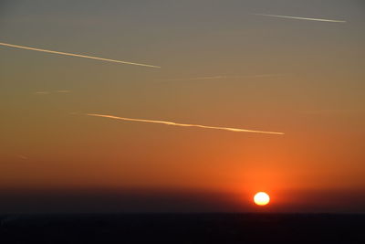 Scenic view of vapor trails in sky at sunset