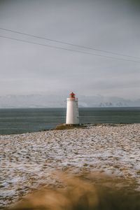 Lighthouse by sea against sky