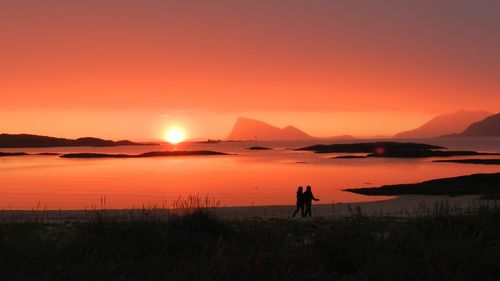 Silhouette people on land against sky during sunset