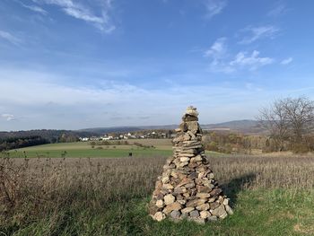 Stack of stones on field against sky