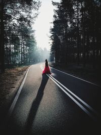 Full length of woman standing on road against trees