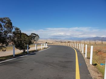 Road by trees against blue sky