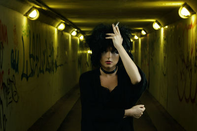 Portrait of young woman standing against wall