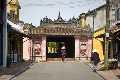 Rear view of people walking on street towards temple