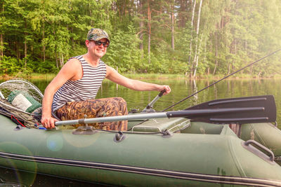 Full length of young man in boat against trees in forest