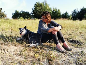 Woman with dog sitting on land