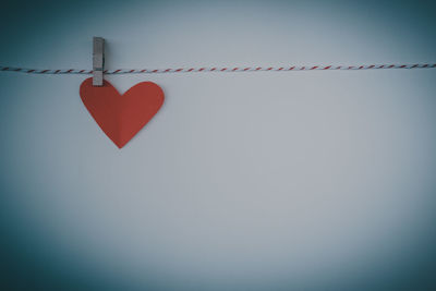 Close-up of heart shape hanging on rope against sky