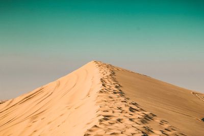 Sand dunes in desert against clear sky