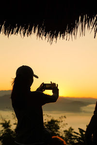 Silhouette man on beach against sky during sunset