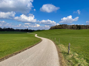 Road amidst field against sky