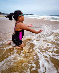 Full length of girl splashing water in sea