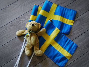 Close-up of teddy bear with swedish flags on wooden table
