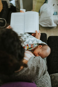 High angle view of mother with baby boy reading book while sitting at home