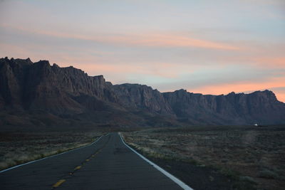 Road leading towards mountains against sky during sunset