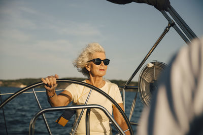 Man wearing sunglasses against boat in sea against sky