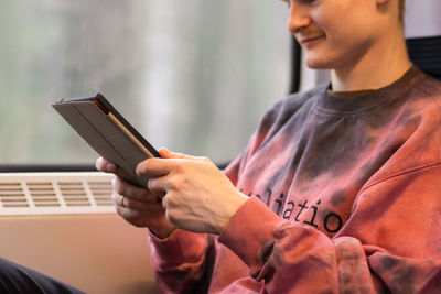 Young man reading e-book when he traveling by train. man sits at the window and using digital tablet