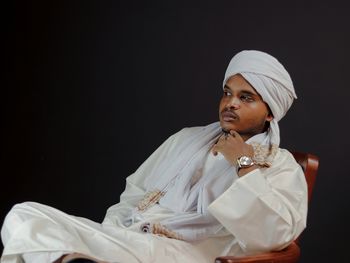 Low angle view of young woman in traditional clothing standing against black background