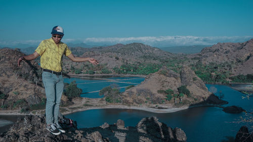 Man standing on rock by mountain against sky