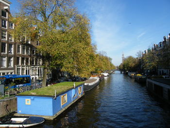 Canal amidst trees and buildings against sky