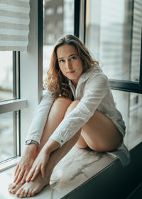 Portrait of young woman sitting on sofa at home