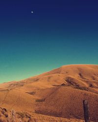 Scenic view of desert against clear blue sky