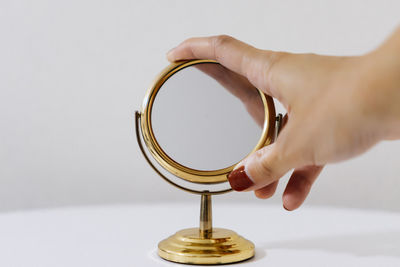 Close-up of hand holding metal against white background