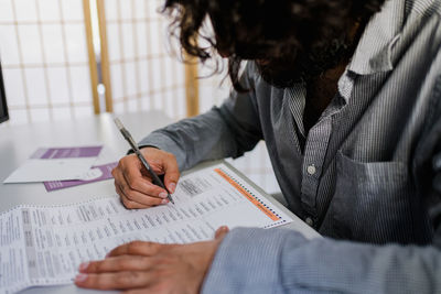 Midsection of man holding paper while sitting on table