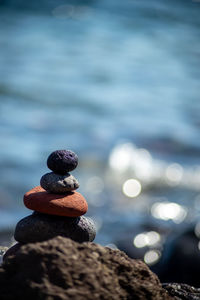 Closeup shot of pebbles stacked on each other in a balance with the blue sea in the background