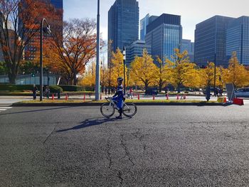 People riding bicycle on road against buildings in city