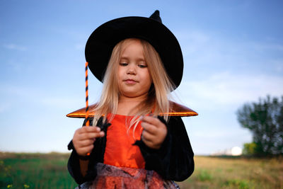 Portrait of girl wearing hat while standing on field