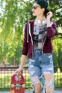 Young woman looking away while standing against trees