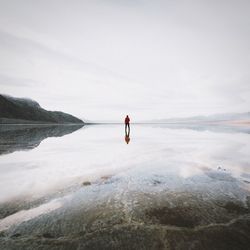 Man standing in sea against sky