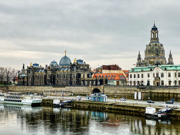 Boats in canal by buildings against sky