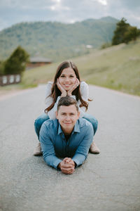 Portrait of happy couple sitting in the middle of the road 